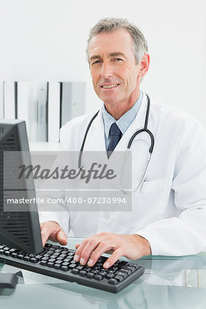 Portrait of a smiling male doctor using computer at the medical office