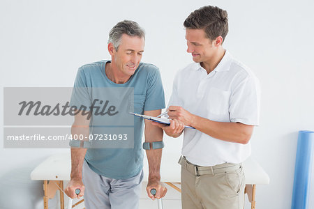 Male therapist discussing reports with a disabled patient in the gym at hospital