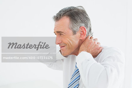 Side view of a mature man suffering from neck pain over white background