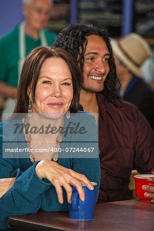 Mixed couple together in cafe with coffee mugs