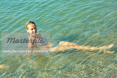 Teen girl on the turquoise sea water surface in shallow coastal area