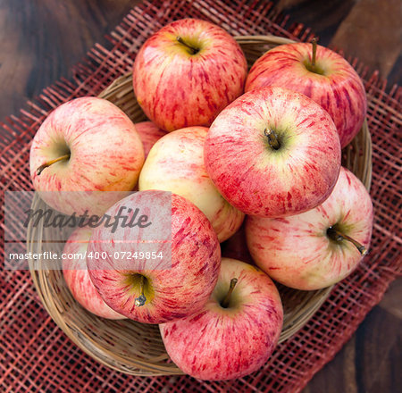 Fresh red apples in basket on the wooden table, top view