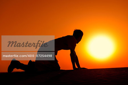 Tired and weaken man on all fours with gold sunset sun disk on background