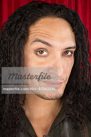 Close up of skeptical Latino man with long hair