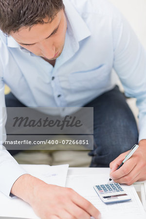 Close-up of a young man with bills and calculator at the table