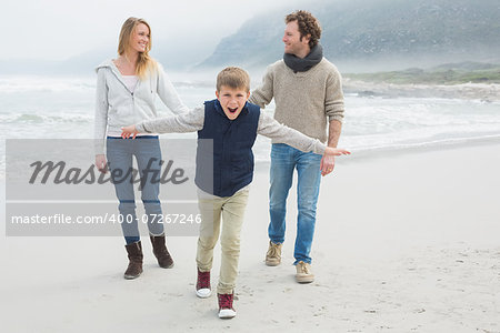 Full length portrait of a happy family of three walking at the beach