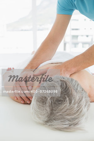 Close-up of a physiotherapist massaging a senior woman's back in the medical office