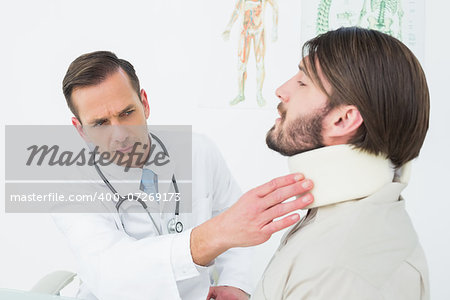 Male doctor examining a patient's neck in the medical office