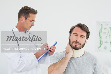 Male doctor examining a patient's sprained neck in the medical office