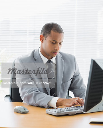 Concentrated young businessman using computer at office desk