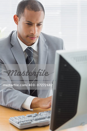 Concentrated young businessman using computer at office desk