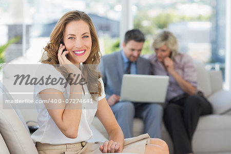 Businesswoman on call with colleagues using laptop in background at home