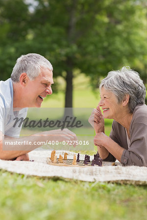 Side view of a happy senior couple playing chess at the park
