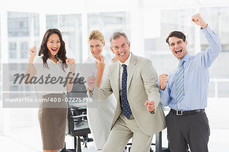 Business team cheering at the camera in the office