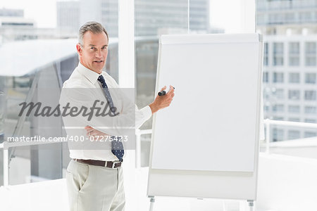 Smiling businessman presenting at whiteboard with marker in the office