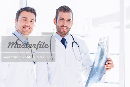 Portrait of two male doctors examining xray in a bright medical office