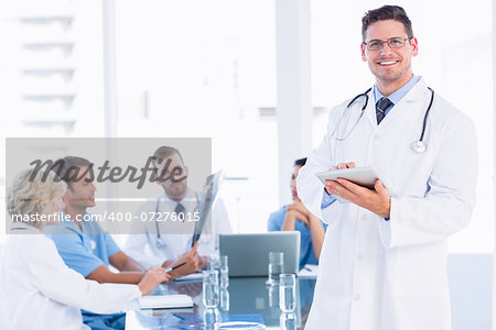 Doctor using digital tablet with colleagues in meeting at a medical office