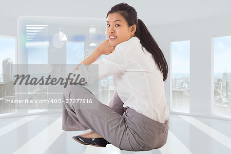 Businesswoman sitting cross legged smiling against steps against blue sky