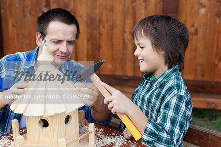 Father and son building a bird house or feeder for the winter time