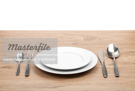 Empty plate and silverware set on wooden table