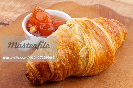 Freshly Baked Croissant and Apricot Jam on Wooden Plate closeup
