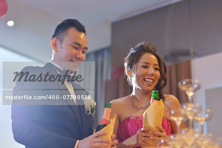 Happy Asian Chinese wedding dinner reception, bride and groom champagne toasting, natural candid photo.