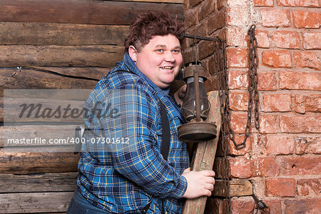 Happy overweight young man standing against a brick wall at the top of a stepladder laughing