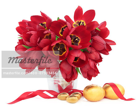 Easter eggs with red tulip flower arrangement and ribbon curl over white background.