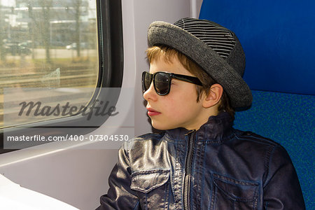 Handsome boy in sunglasses rides on a train