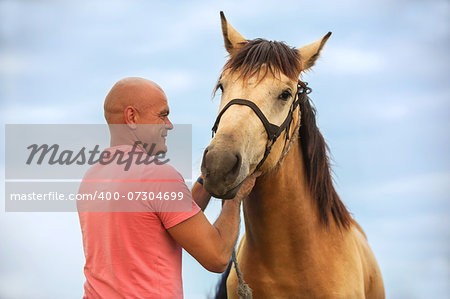 Photo bald man walks with a horse in the field