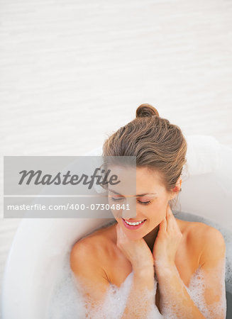 Portrait of happy young woman laying in bathtub