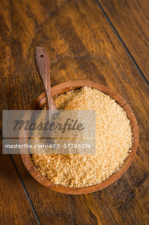 Cane sugar in a wooden bowl with a spoon.