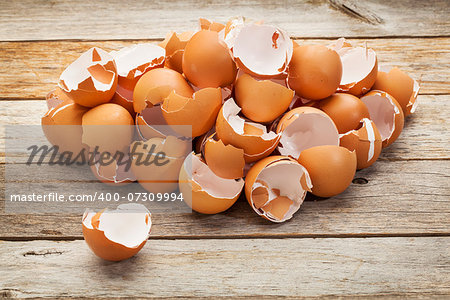a pile of broken  empty brown chicken eggshells on a rustic wooden table