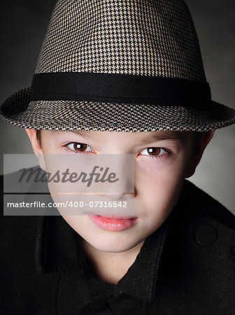 Young boy wearing a hat on black background