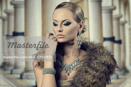 close-up fashion portrait of sensual blond girl with luxury style, posing with elegant hair-style and make-up and wearing fur shawl and rich shiny jewellery. Aristocratic expression