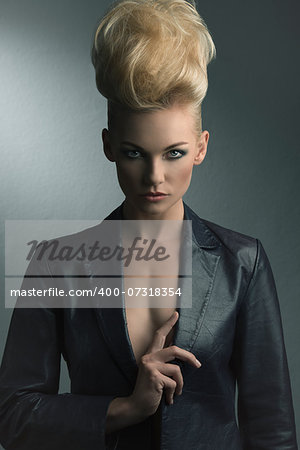 portrait of pretty blonde girl with fashion look, creative modern hair-style and leather jacket, looking in camera