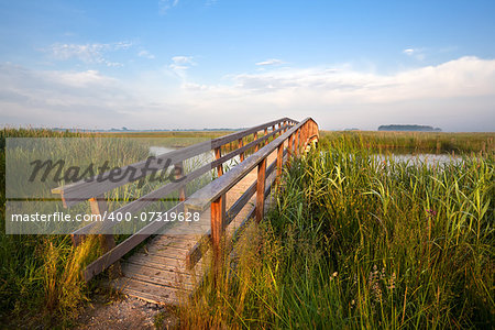 long wooden bridge for bicycles over river in morning