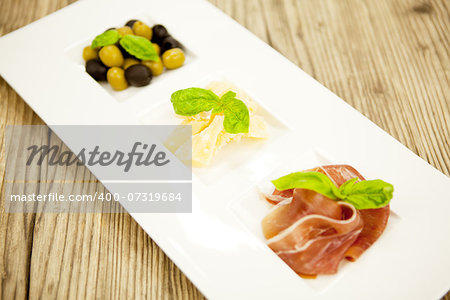 deliscious antipasti plate with parma parmesan olives on wooden background
