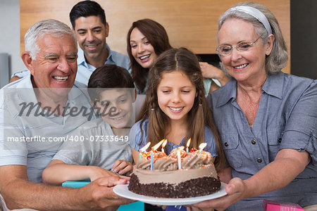 Portrait of extended family sitting on sofa with cake in the living room at home