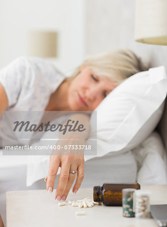 Closeup of a mature woman sleeping in bed with pills in foreground at home