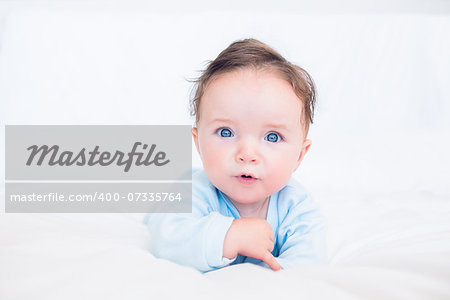 Portrait of innocent baby boy with blue eyes lying in bed
