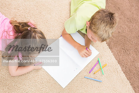 Siblings colouring on the rug at home in living room