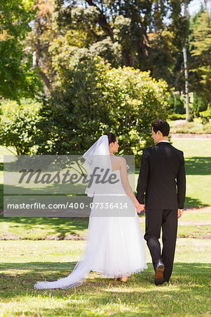 Full length rear view of a newlywed couple walking in the park