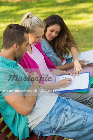 Side view of a three college friends sitting on bench at the campus