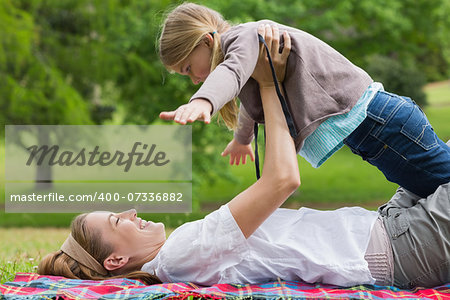 Side view of a smiling mother carrying daughter at the park