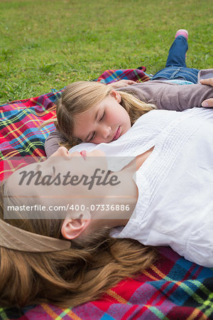 Side view of a relaxed mother and daughter lying at the park