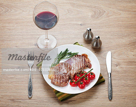 Sirloin steak with rosemary and cherry tomatoes on a plate with wine. View from above
