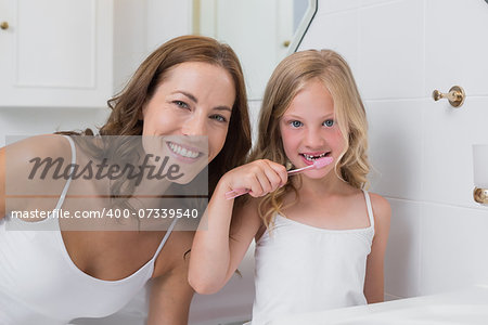 Portrait of mother with daughter brushing teeth in the bathroom