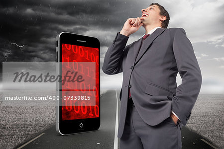 Thoughtful businessman with hand on chin against stormy landscape with street