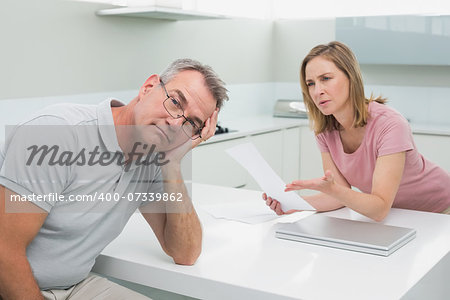 Unhappy couple having an argument over a bill in the kitchen at home